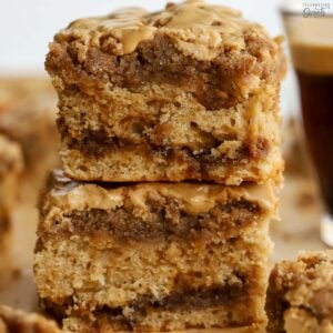 Two slices of crumb cake stacked on top of each other with a glass of coffee in the background.