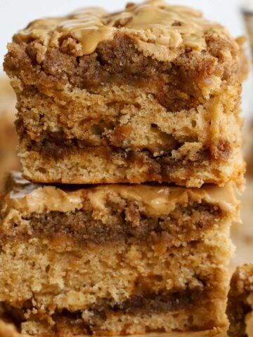 Two slices of crumb cake stacked on top of each other with a glass of coffee in the background.