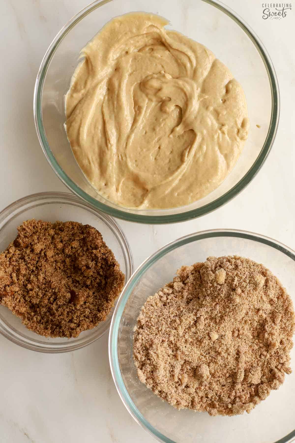 Three glass bowls: one filled with cake batter, one with brown sugar, one with crumb topping.