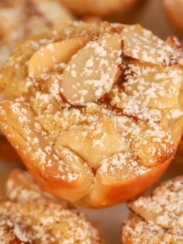 Closeup of an almond croissant bite dusted with powdered sugar.