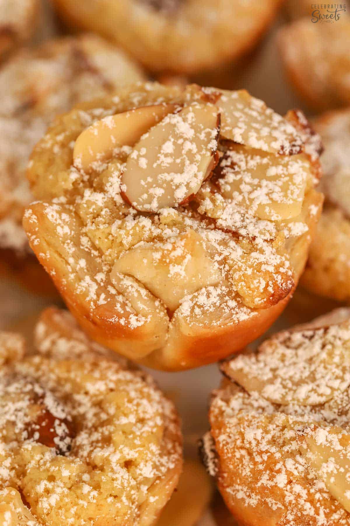 Closeup of an almond croissant bite dusted with powdered sugar.