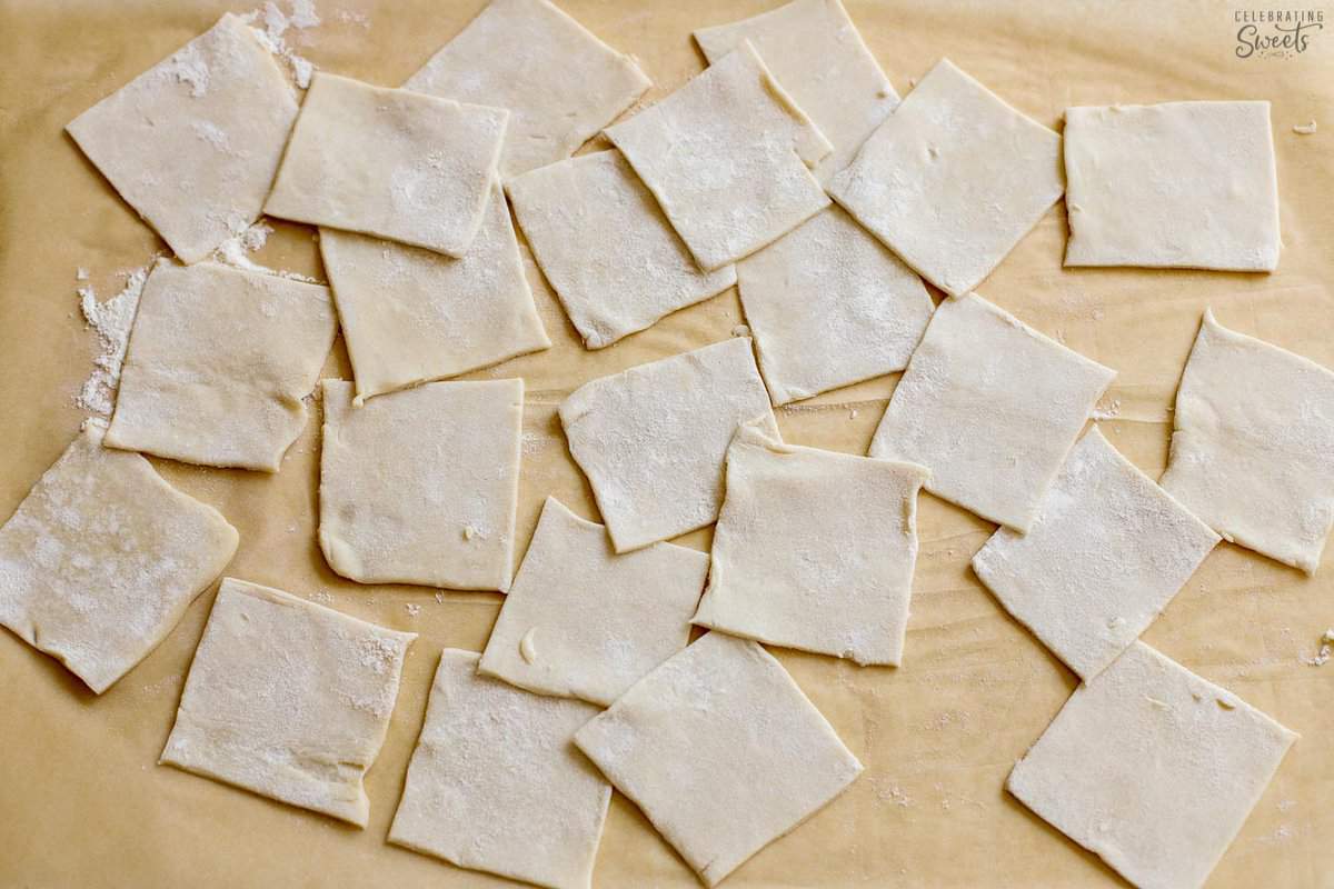 24 squares of puff pastry on a piece of parchment paper.