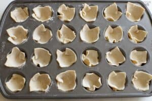 Unbaked puff pastry in a mini muffin pan.