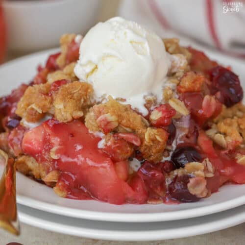 Apple cranberry crisp topped with vanilla ice cream on a white plate.