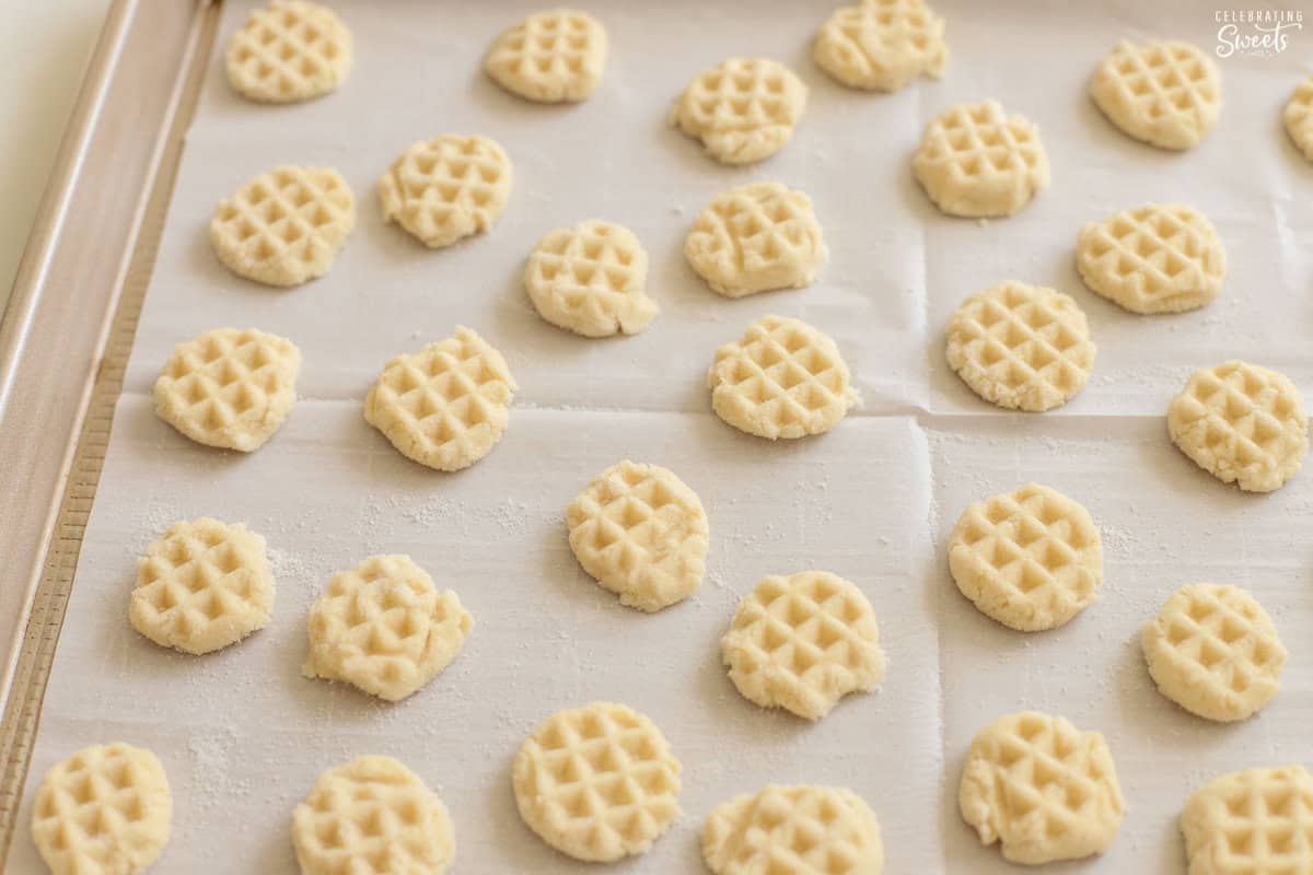 Unbaked sugar cookies on a parchment-lined baking sheet.