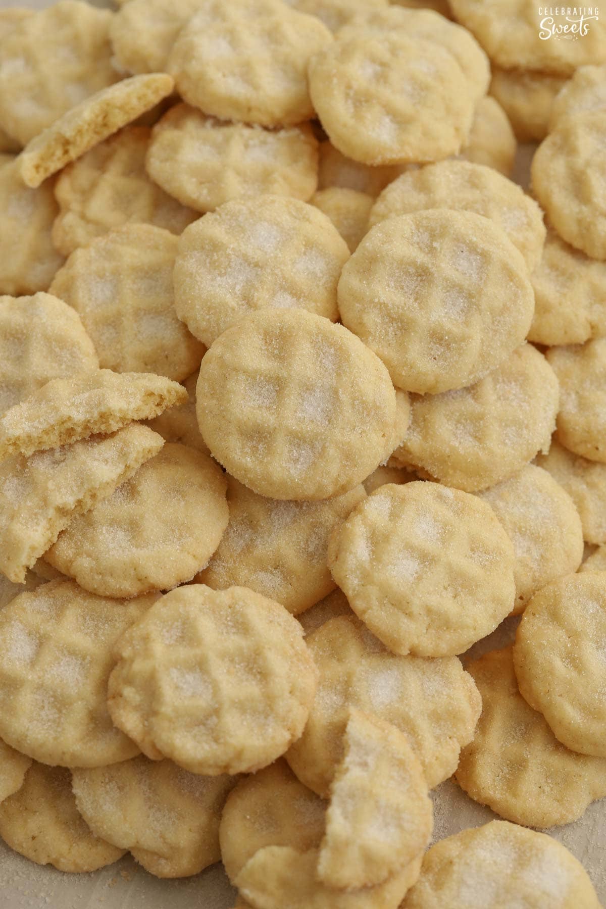 A pile of mini sugar cookies on a baking sheet.