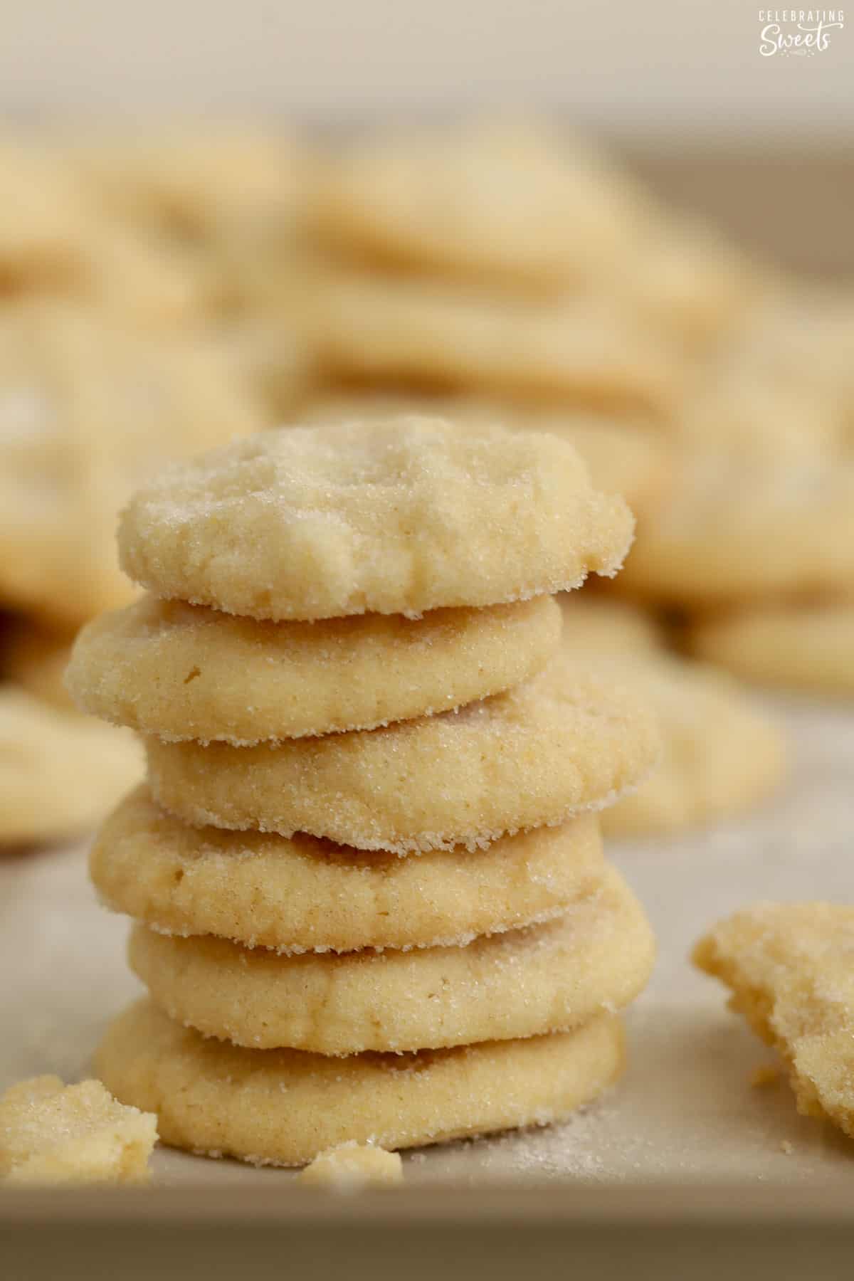 A stack of mini sugar cookies on a parchment-lined baking sheet,