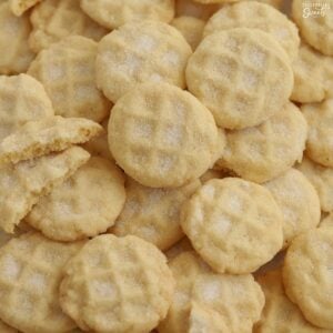 A pile of mini sugar cookies on a baking sheet.