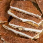 Five pieces of churro toffee overlapping on parchment paper.