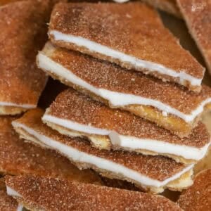 Five pieces of churro toffee overlapping on parchment paper.