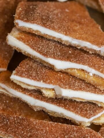 Five pieces of churro toffee overlapping on parchment paper.