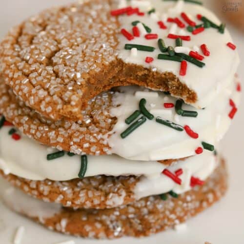 Stack of ginger molasses cookies dipped in white chocolate and covered in red and green sprinkles.