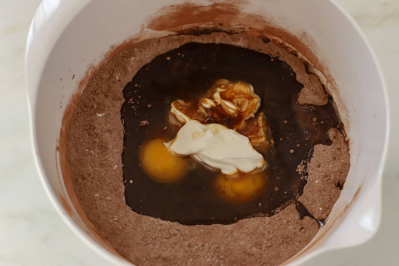 Chocolate cake batter in a white bowl (flour, cocoa, eggs, sour cream, sugar, oil).