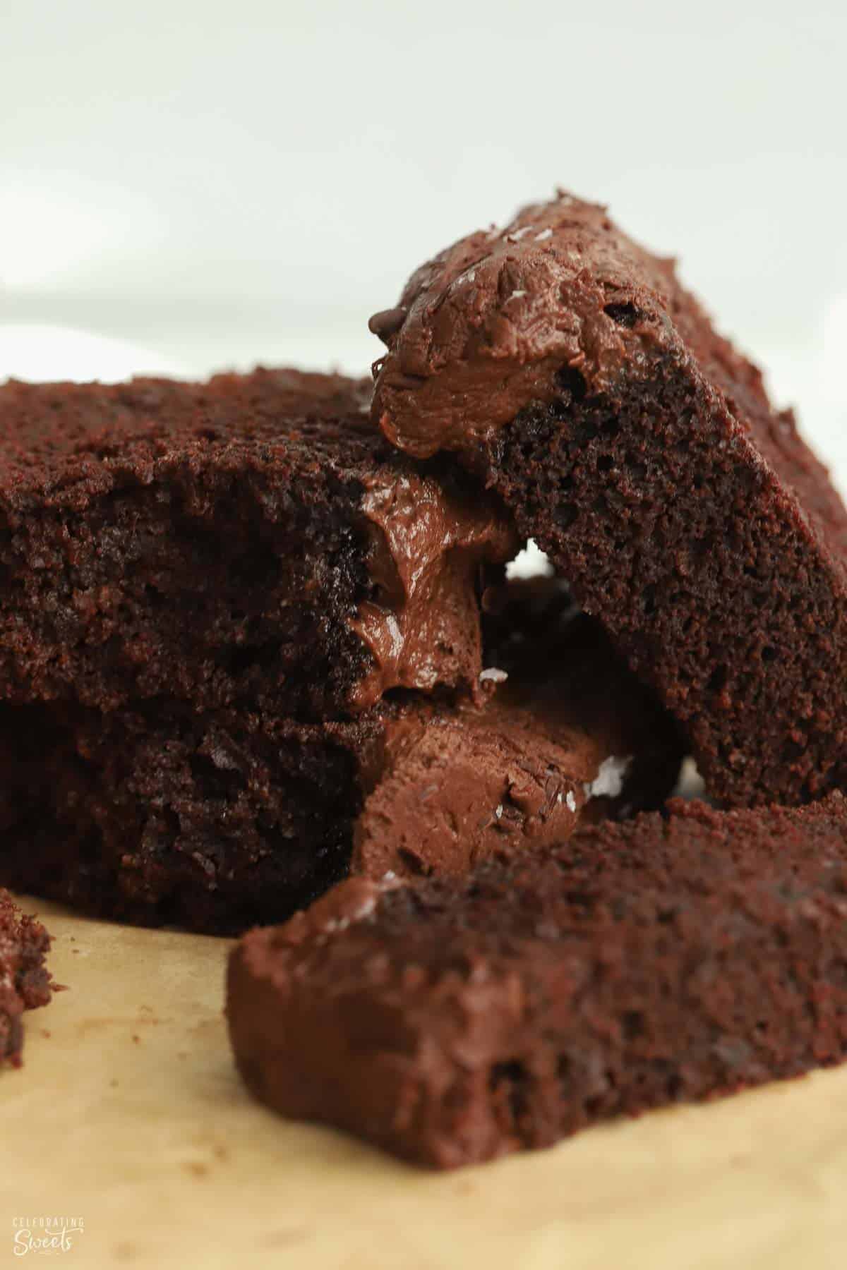 Four slices of chocolate loaf cake stacked on a piece of parchment paper.