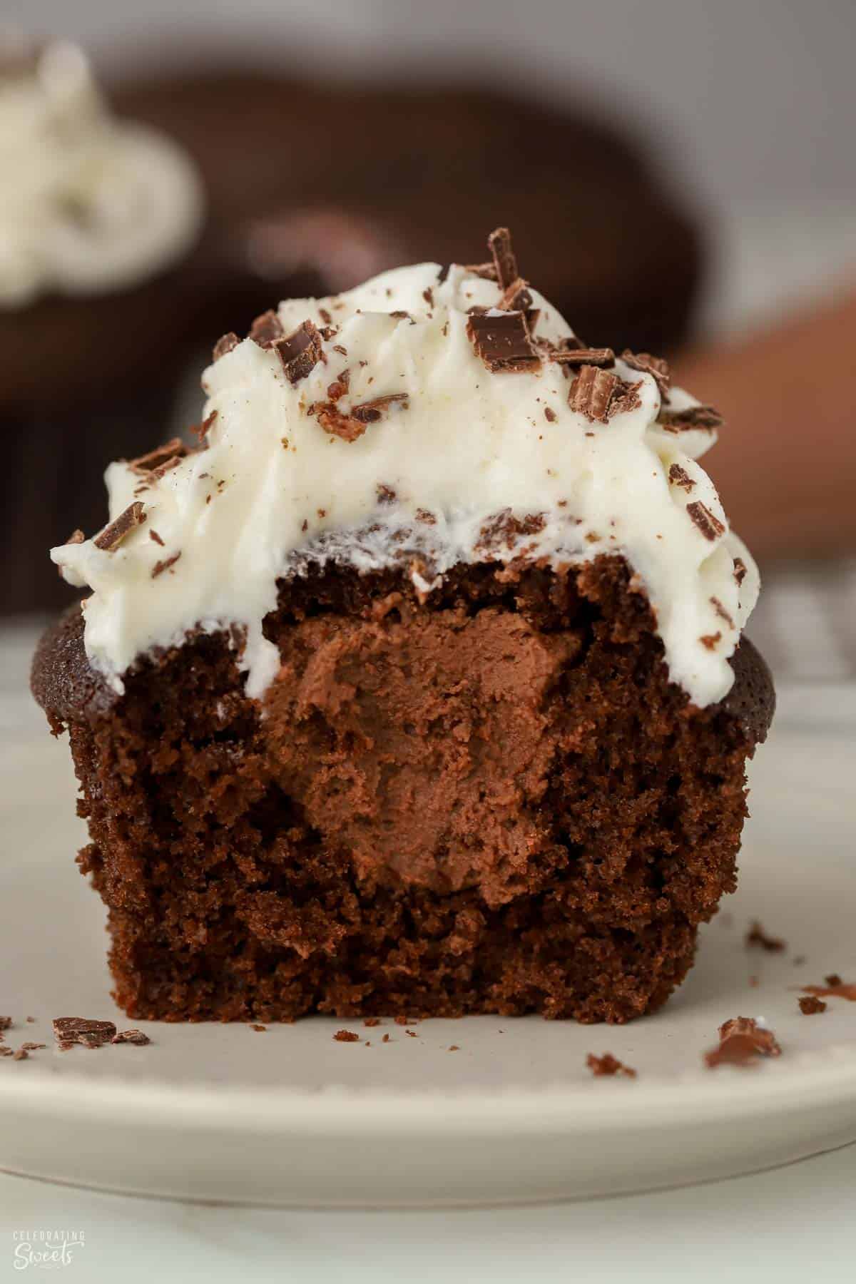 Half of a chocolate cupcake filled with chocolate mousse topped with white frosting.