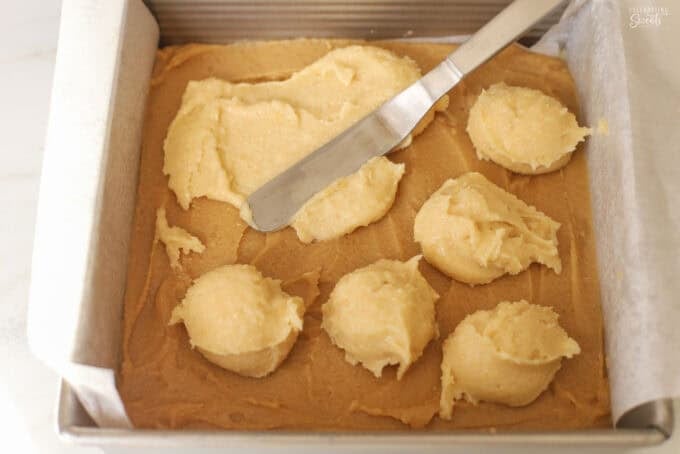 Almond blondie batter in a parchment paper lined square baking dish.