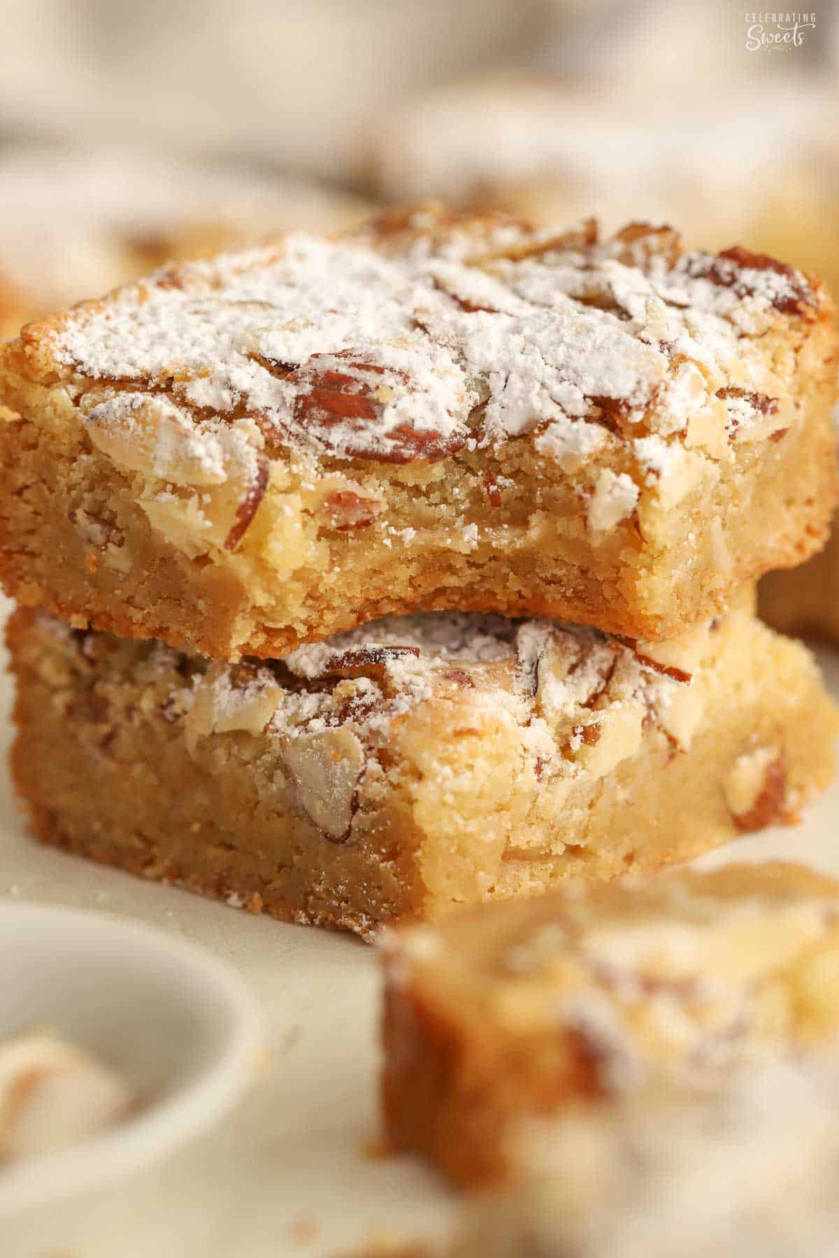 Two almond blondies topped with powdered sugar stacked on top of each other