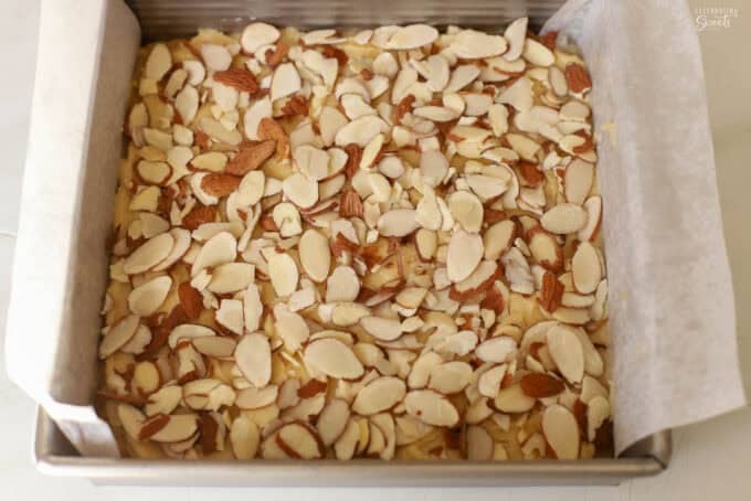 Unbaked almond blondies in a square baking pan topped with sliced almonds.