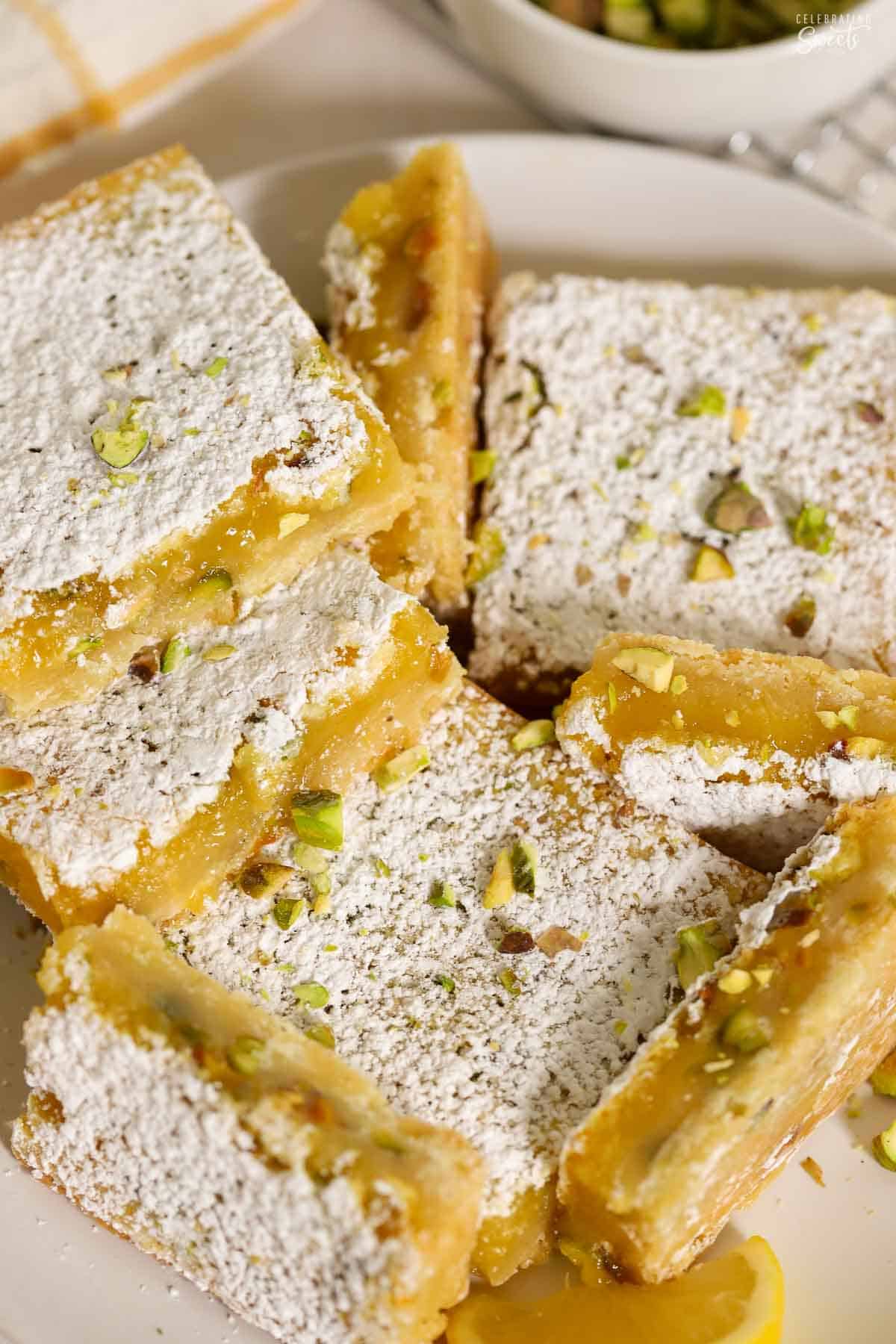 Lemon pistachio bars arranged on a white plate.