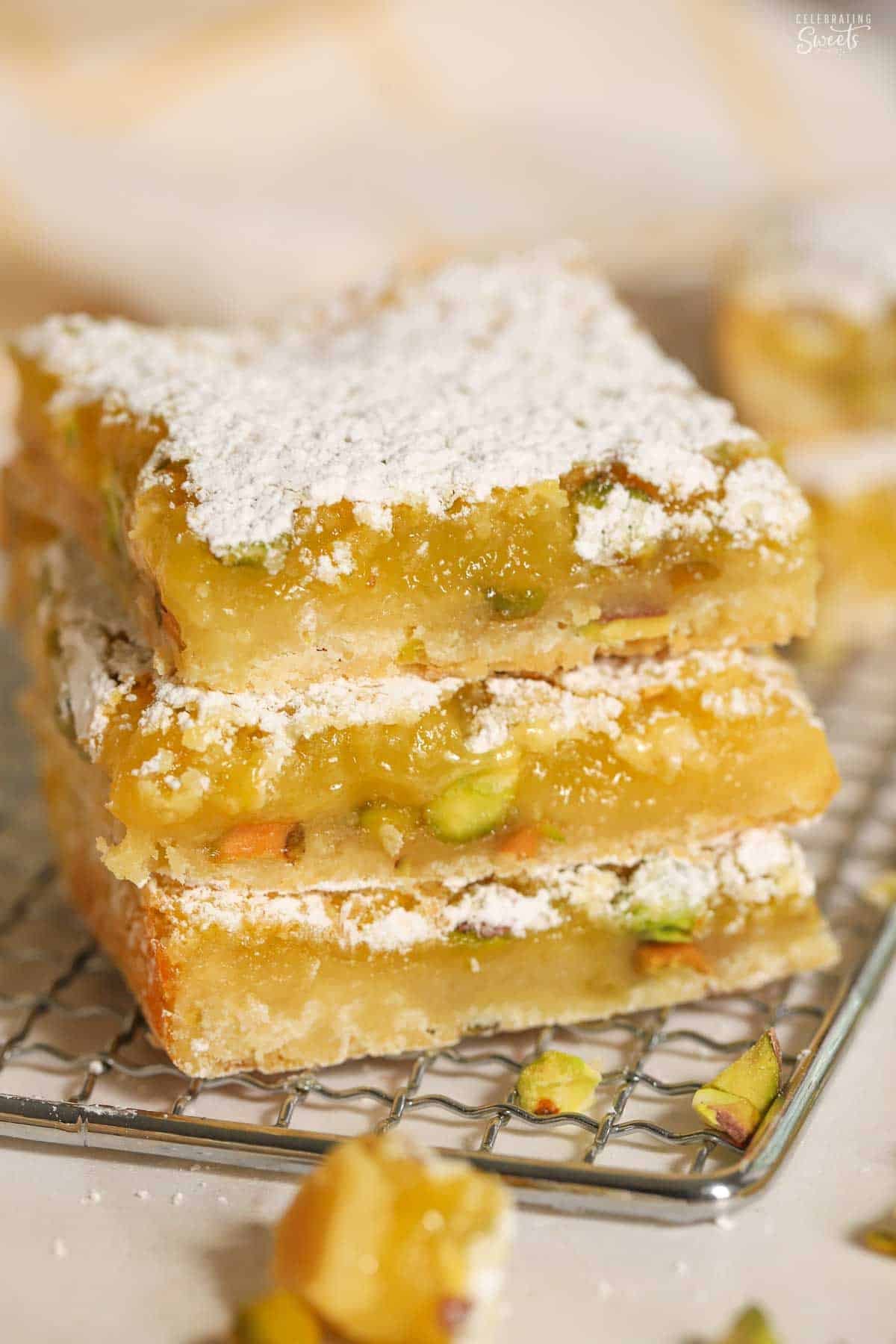 Stack of three lemon pistachio bars on a wire rack.