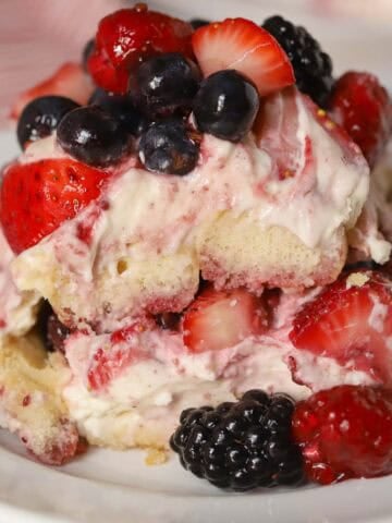 Berry tiramisu on a white plate garnished with mixed berries.