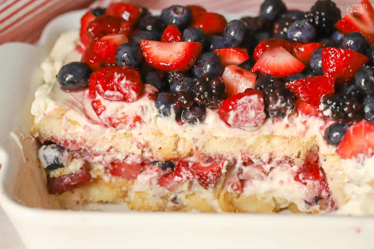 Berry tiramisu in a white baking dish topped with mixed berries.