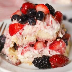 A serving of berry tiramisu on a white plate garnished with mixed berries.