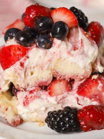A serving of berry tiramisu on a white plate garnished with mixed berries.