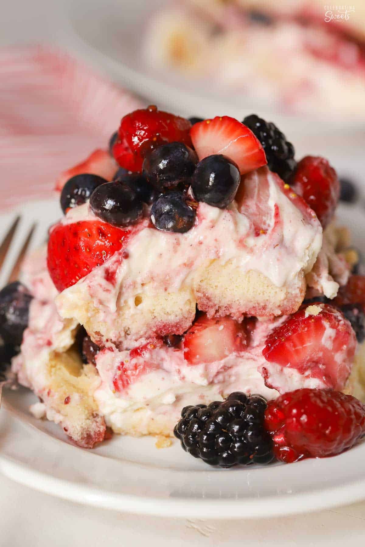 A serving of berry tiramisu on a white plate garnished with mixed berries.