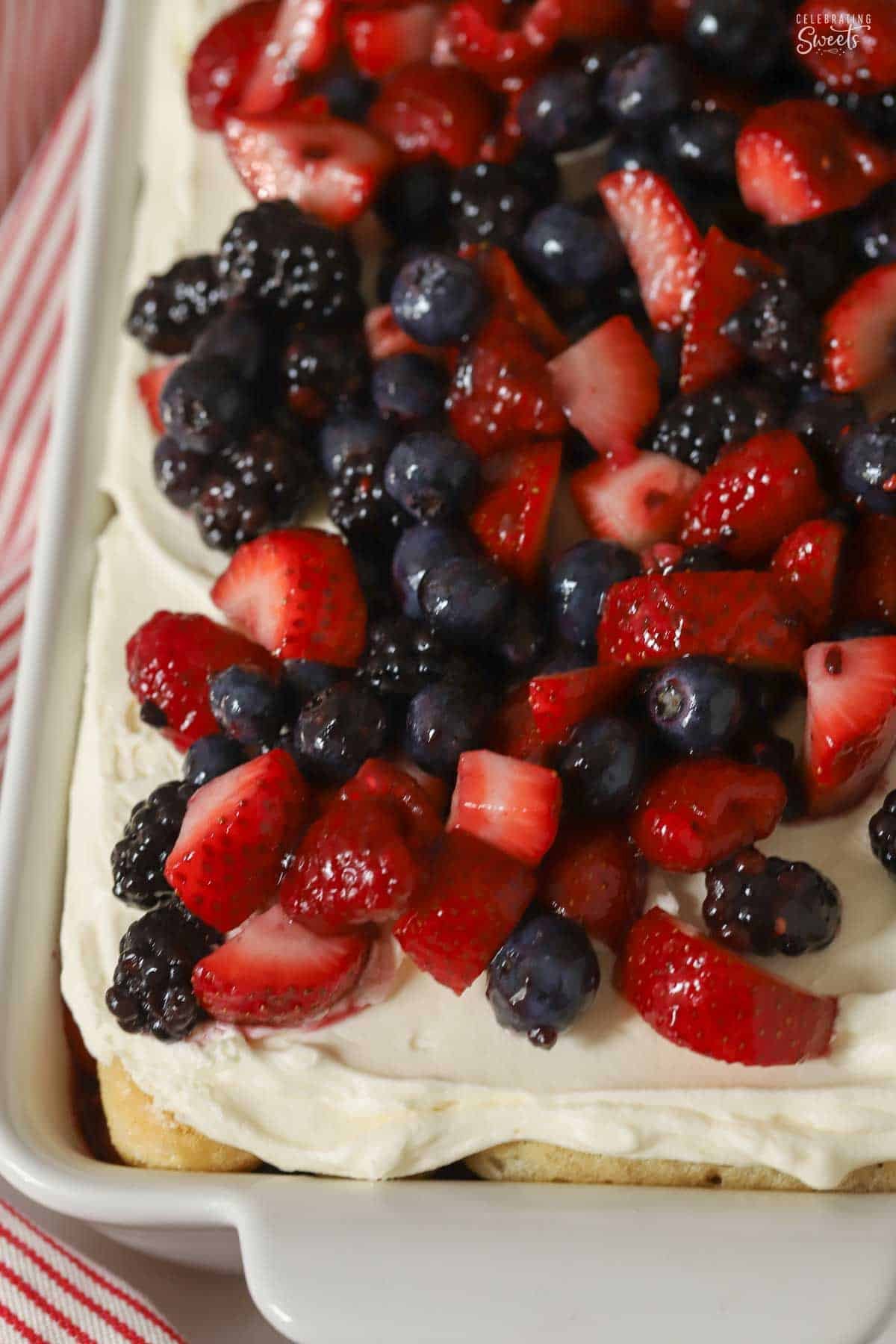 Overhead shot of berry tiramisu in a white baking dish topped with mixed berries.