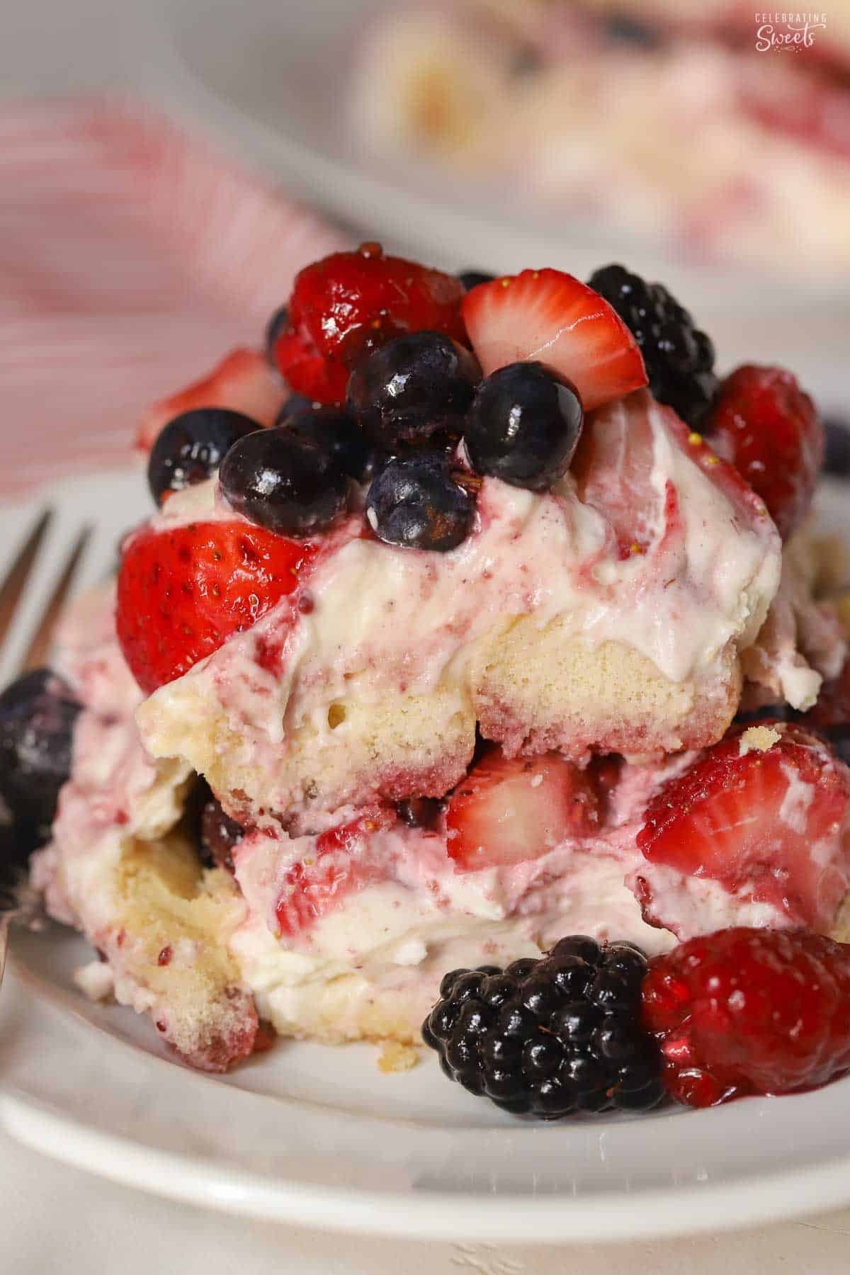 A serving of berry tiramisu on a white plate garnished with mixed berries.