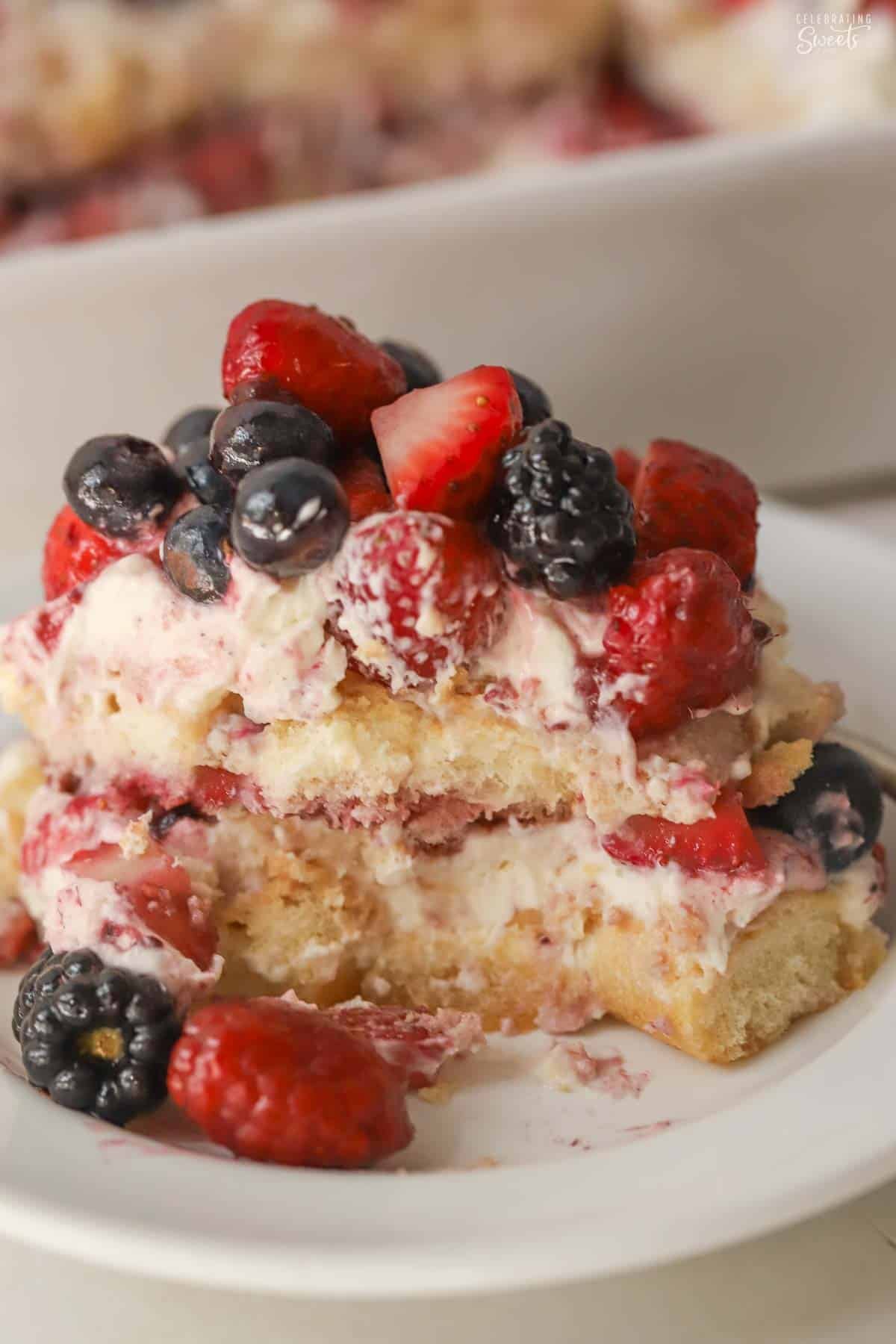 A serving of berry tiramisu on a white plate topped with fresh berries.