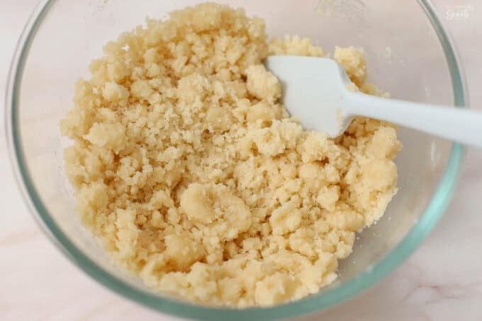 Cobbler topping in a glass bowl with a grey spatula.