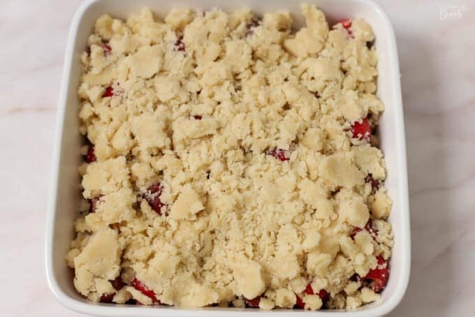 Unbaked cherry cobbler in a white square baking dish.