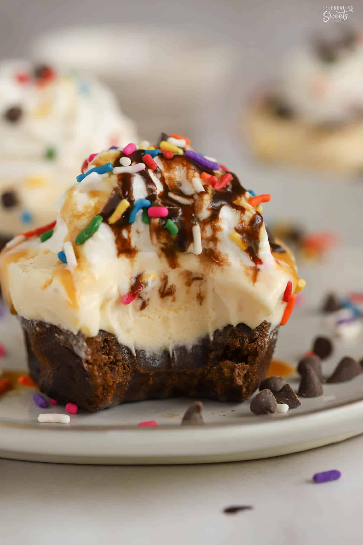 Brownie ice cream cupcake with a bite taken out of it on a grey plate.