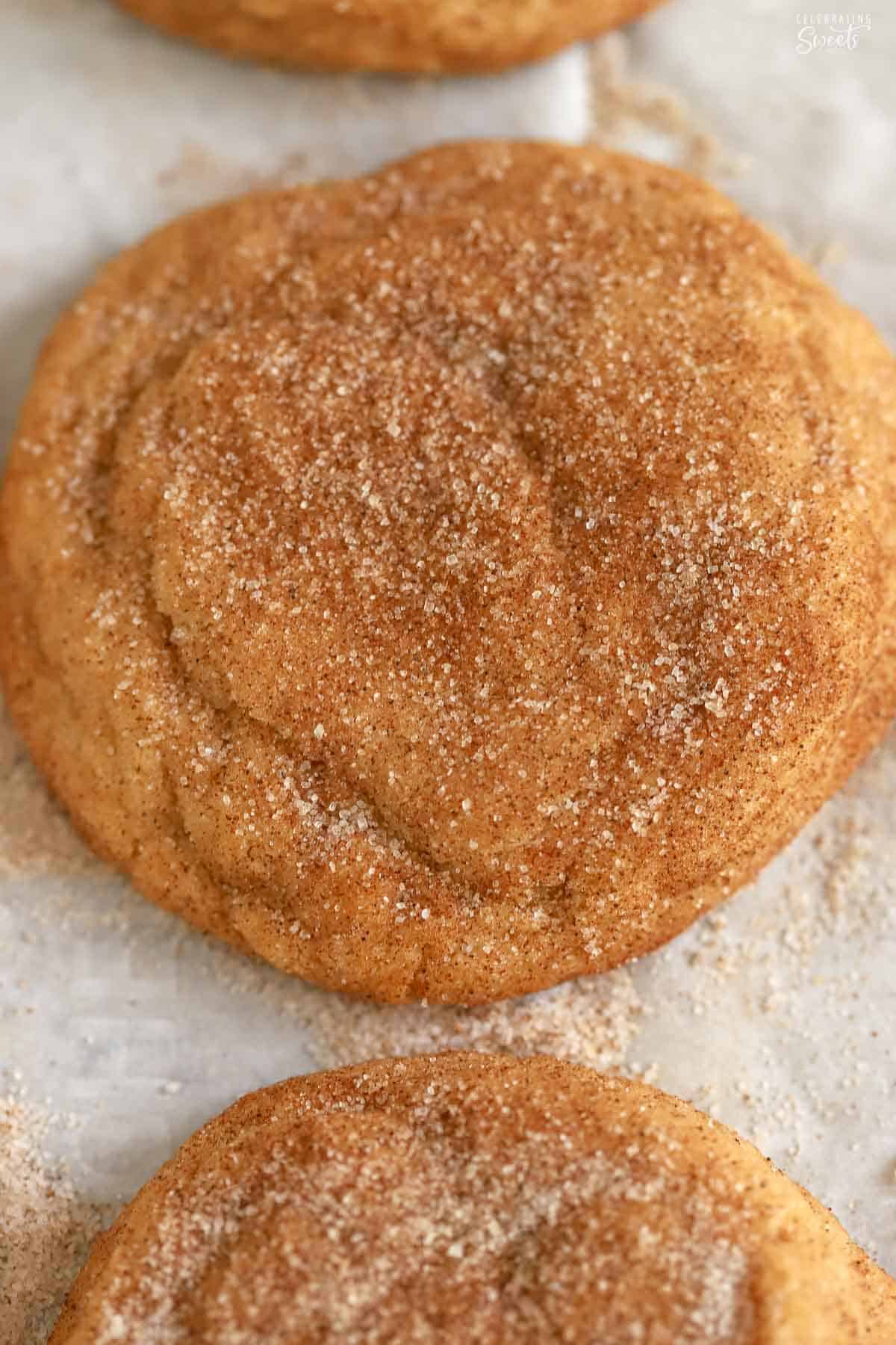 Snickerdoodle cookie covered in cinnamon sugar on a parchment-lined baking sheet.