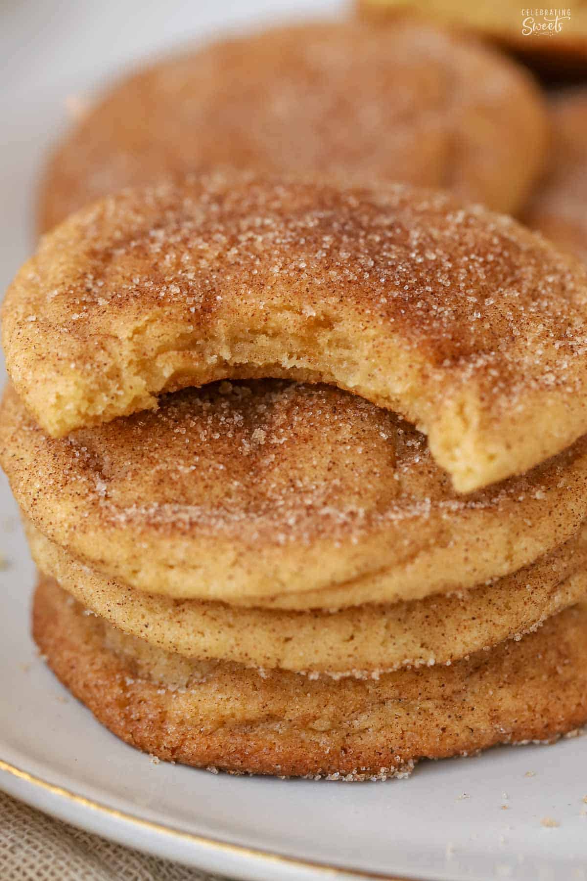 Four snickerdoodle cookies stacked on top of each other on a grey plate.