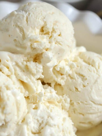 Four scoops of vanilla ice cream in a white bowl.