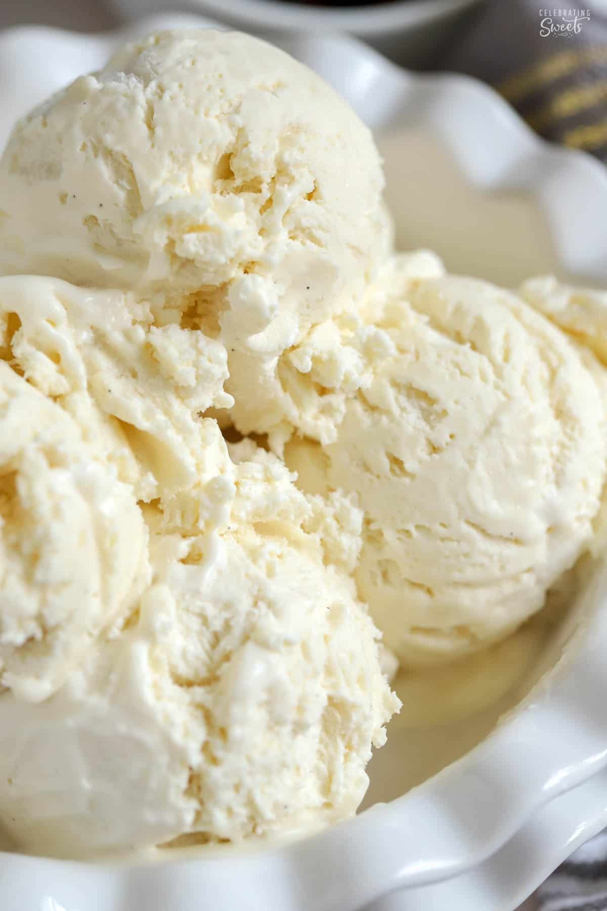 Four scoops of vanilla ice cream in a white bowl.