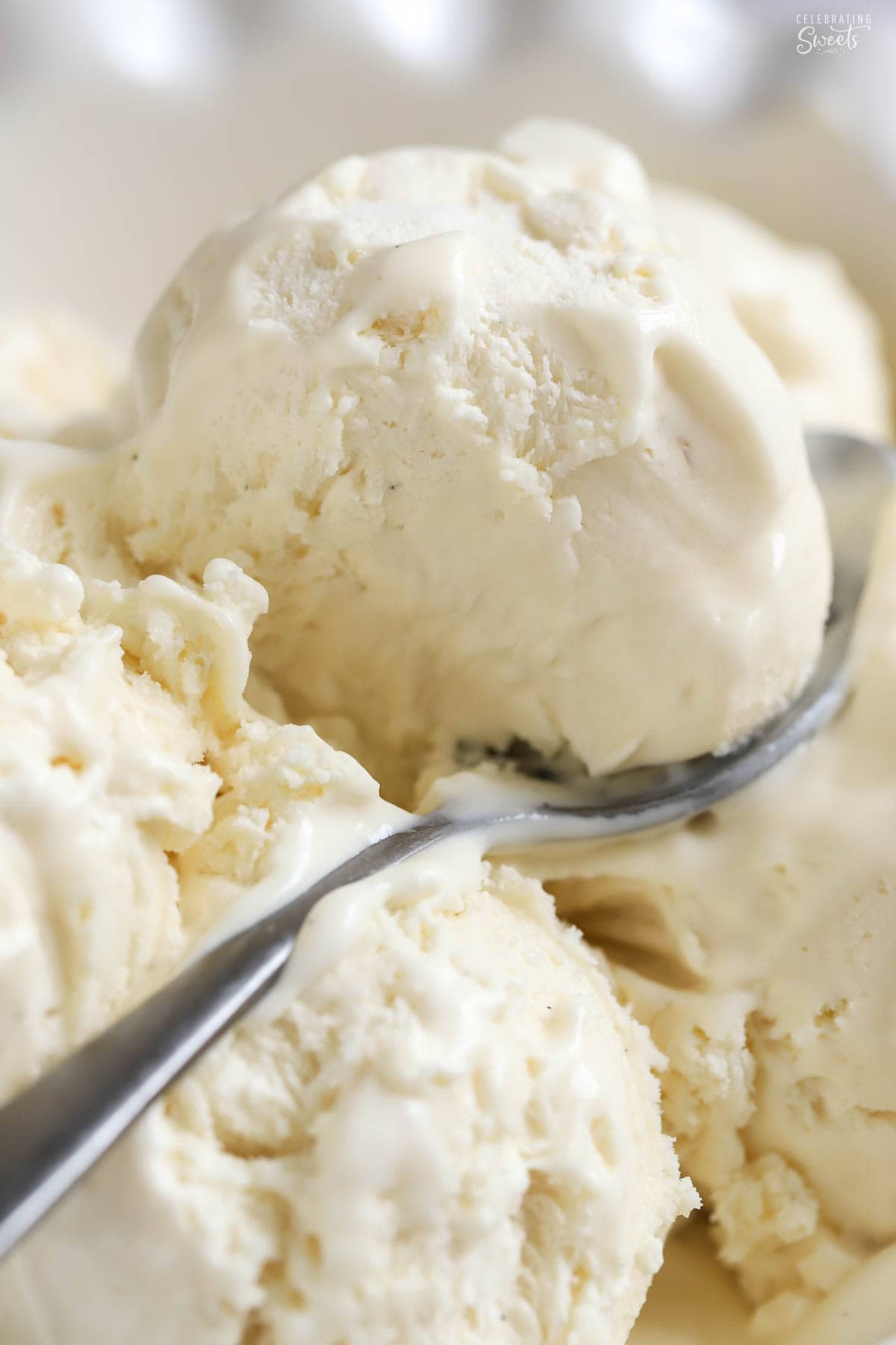 Vanilla ice cream piled in a white bowl with a silver spoon.