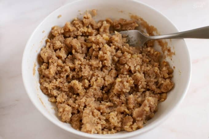 Unbaked crumb topping in a white bowl with a silver fork.