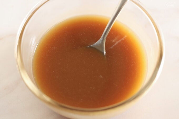 Brown sugar caramel sauce in a glass bowl with a silver spoon.