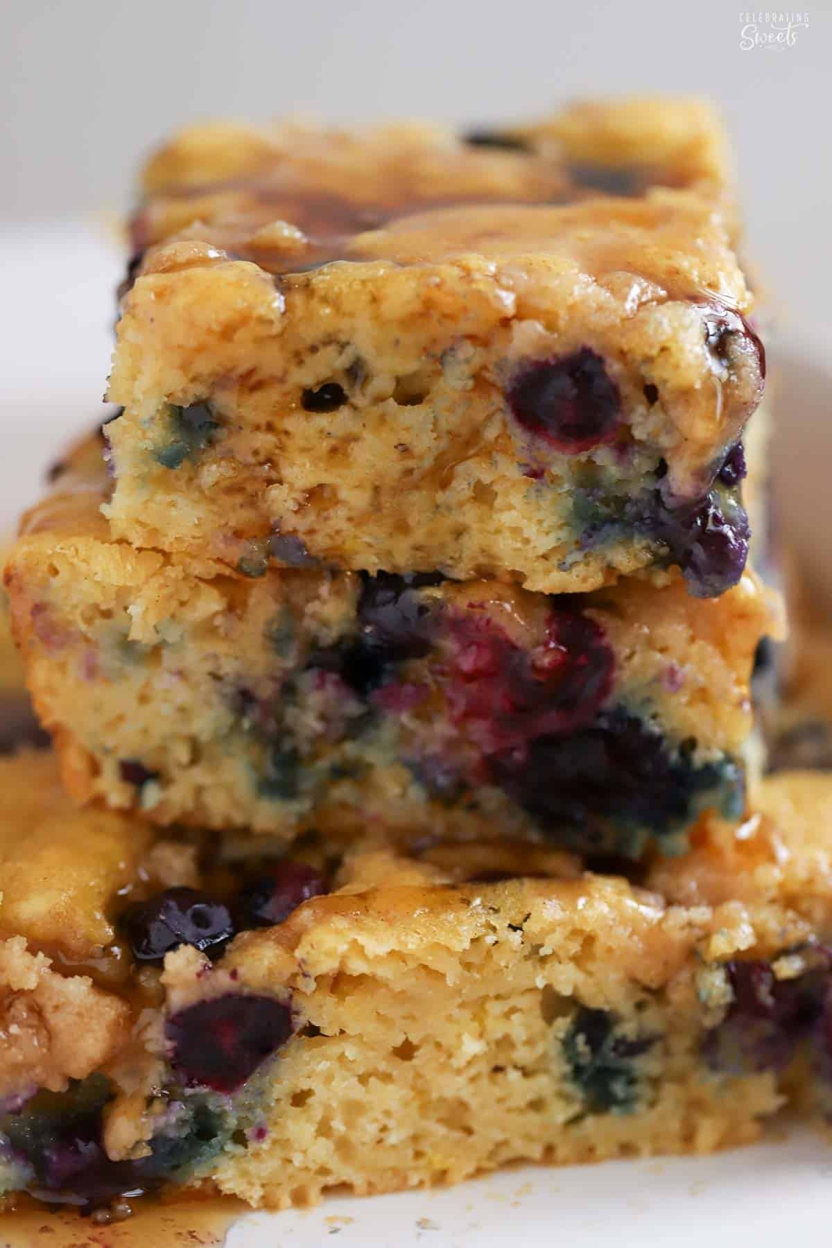 Three pieces of blueberry pancake casserole stacked on top of each other in a white baking dish.
