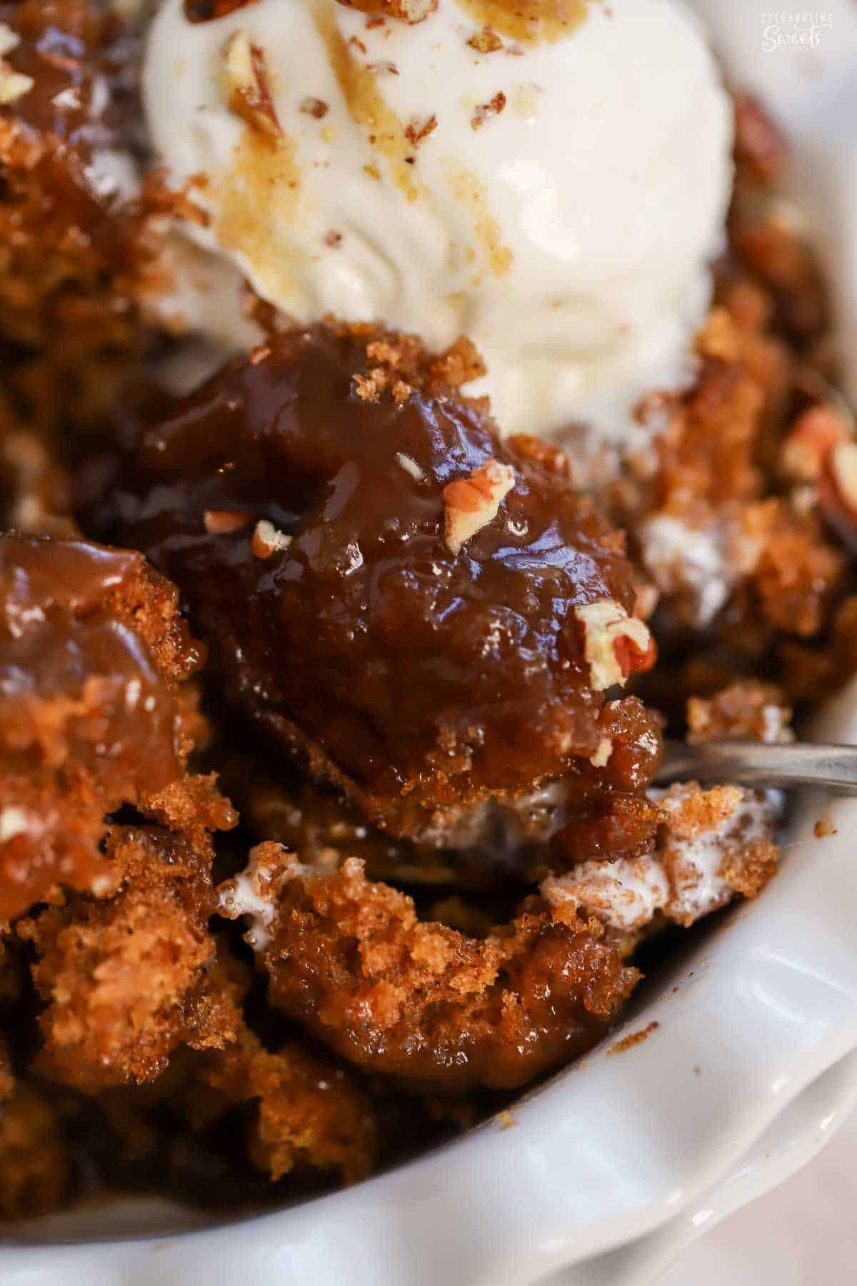 Closeup of pumpkin pudding cake in a white bowl topped with pecans.