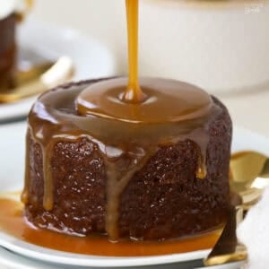 Toffee sauce being poured on sticky toffee pudding.