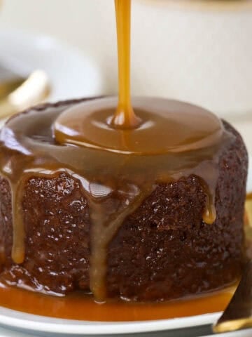 Toffee sauce being poured on sticky toffee pudding.