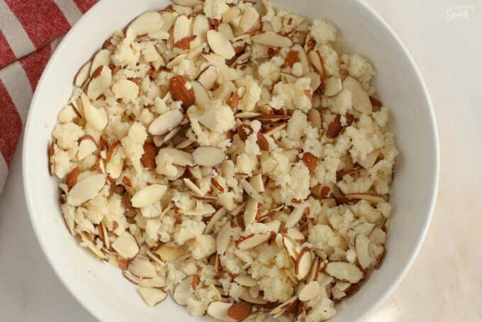 Almond streusel in a white bowl next to a red striped napkin.
