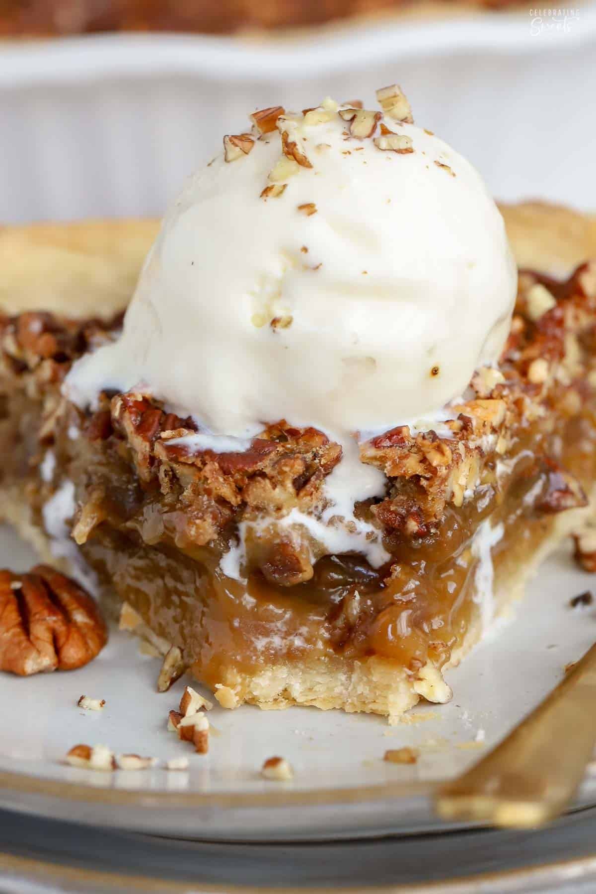 A slice of pecan pie on a grey plate with a bite taken out of it.