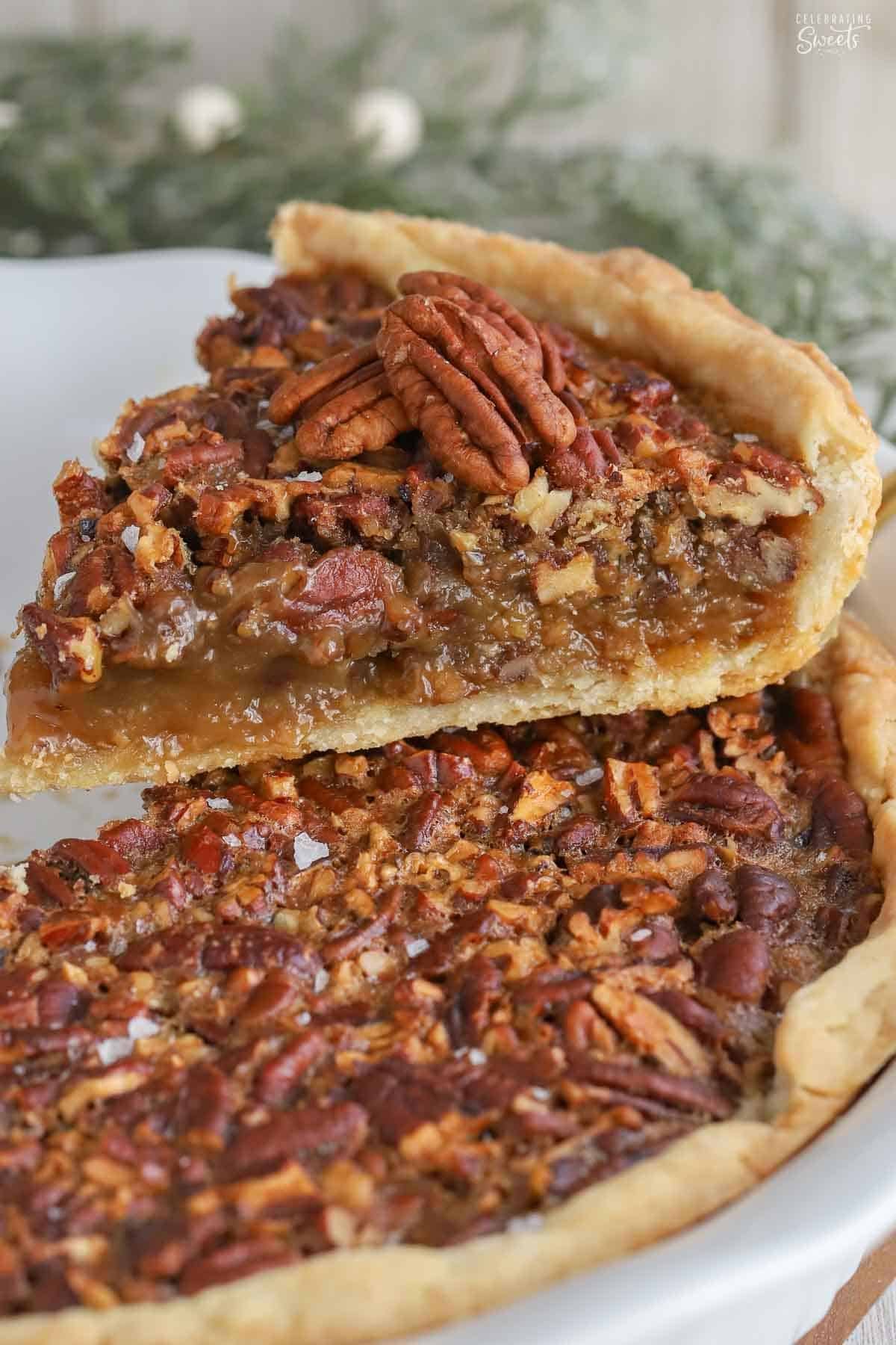 Slice of pecan pie stacked on top of a whole pecan pie.