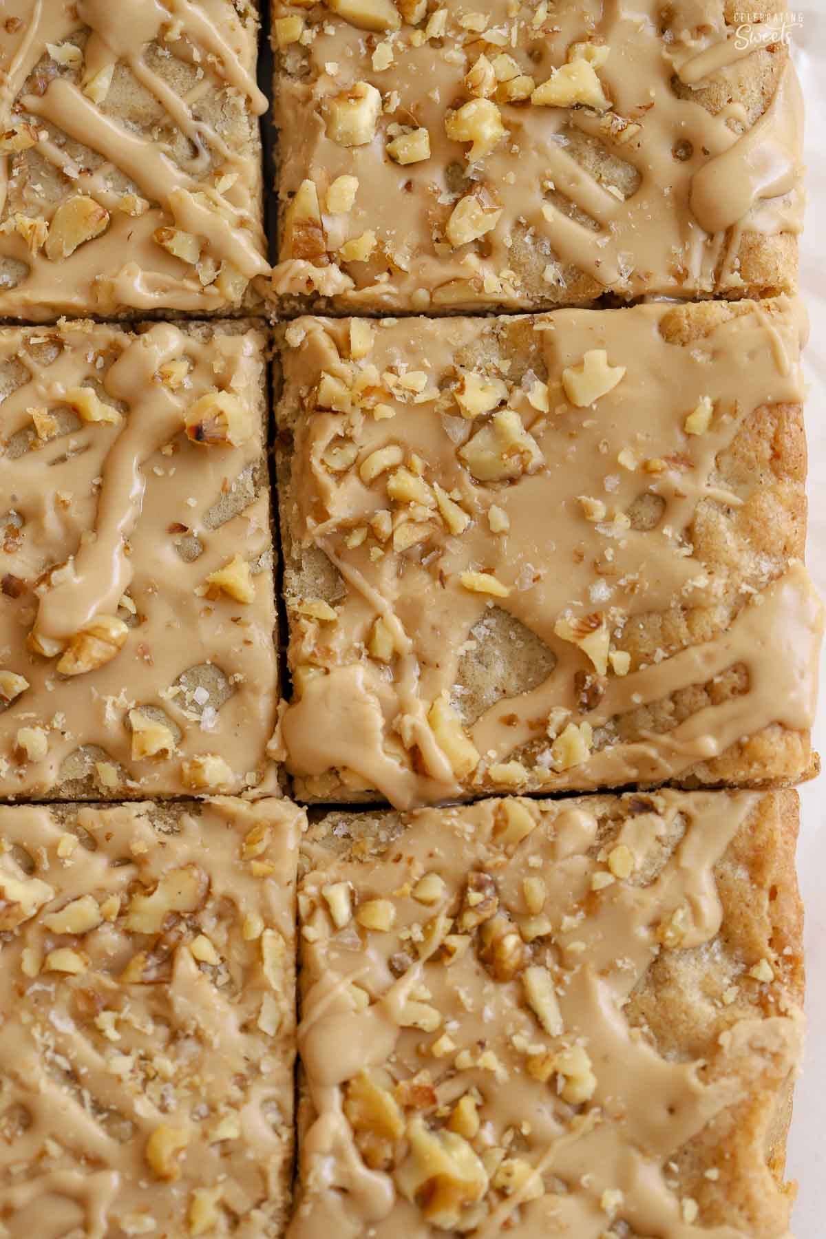 Closeup of six blondie bars topped with light brown icing and chopped walnuts.